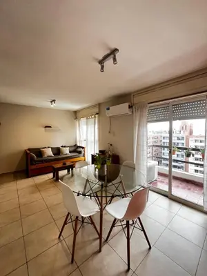 a living room with a glass table and chairs and a bed at El Abrojal - Departamento con Estacionamiento , zona Patio Olmos in Cordoba
