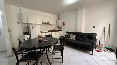 a living room with a table and a black couch at Serena in Villa Carlos Paz