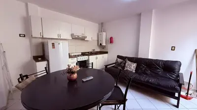 a living room with a table and a black couch at Serena in Villa Carlos Paz