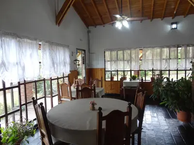 a dining room with a table and chairs and windows at Hostería Lida in Merlo