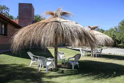 a group of chairs sitting under a straw umbrella at Cabañas Babin Kuk in Merlo