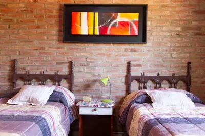 two beds in a room with a painting on the wall at Complejo Utopia-Chacras de la Primavera, Tanti in Tanti