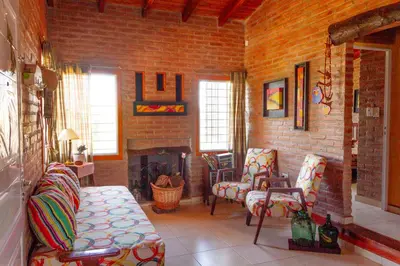 a living room with two chairs and a fireplace at Complejo Utopia-Chacras de la Primavera, Tanti in Tanti
