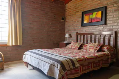 a bedroom with a bed and a brick wall at Complejo Utopia-Chacras de la Primavera, Tanti in Tanti