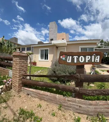 a house with a sign in front of a fence at Complejo Utopia-Chacras de la Primavera, Tanti in Tanti