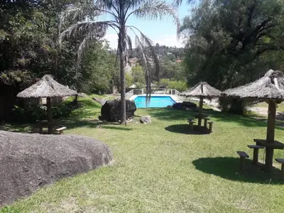a yard with a swimming pool and some umbrellas at Departamentos Carlos Paz bajada al lago in Villa Carlos Paz