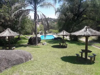 a yard with tables and umbrellas and a swimming pool at Departamentos Carlos Paz bajada al lago in Villa Carlos Paz