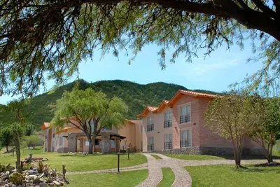 a large building with a mountain in the background at Posada La Soñada in Villa General Belgrano
