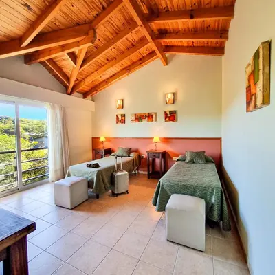 a bedroom with two beds and a table and chairs at Posada La Soñada in Villa General Belgrano