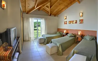 a living room with two beds and a tv at Posada La Soñada in Villa General Belgrano