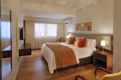 a hotel room with a bed with orange pillows at Altos de Belgrano Hotel Cabañas Golf y Spa in Villa General Belgrano
