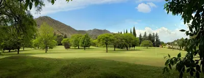 a golf course with trees and mountains in the background at Altos de Belgrano Hotel Cabañas Golf y Spa in Villa General Belgrano