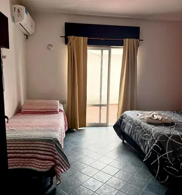 a bedroom with two beds and a sliding glass door at Atenea in Villa Carlos Paz