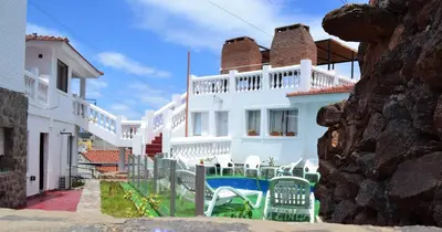 a white house with chairs in front of it at Atenea in Villa Carlos Paz