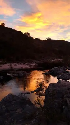 a sunset over a body of water with rocks at Cuesta los Robles -Casas Serranas- in Villa Icho Cruz