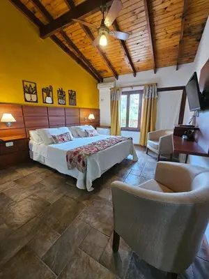 a bedroom with a bed and a couch and a chair at Posada Aitue in Villa General Belgrano