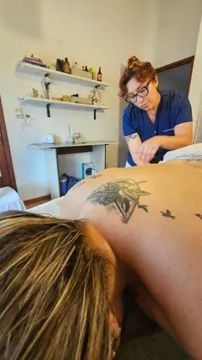 a man getting a tattoo on the back of a woman at Posada Aitue in Villa General Belgrano