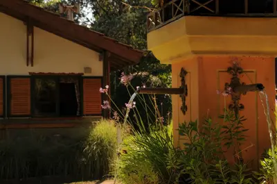 a house with a garden with flowers in front of it at Cabañas Alpendorf in Villa General Belgrano