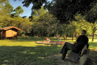 a man sitting on a bench in a park at Cabañas Alpendorf in Villa General Belgrano