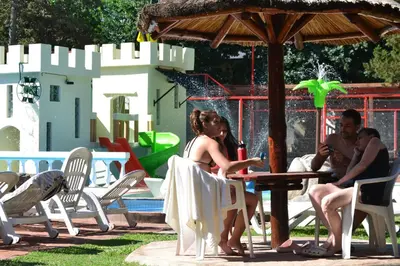 a group of people sitting at a table near a water park at Cabañas Alpendorf in Villa General Belgrano