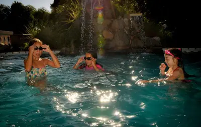 three girls in a swimming pool with a fountain at Cabañas Alpendorf in Villa General Belgrano