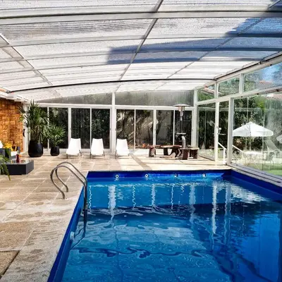 a swimming pool in a house with a glass extension at Posada Mia Nonna in Villa General Belgrano