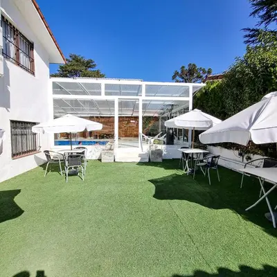 a patio with white umbrellas and chairs and a pool at Posada Mia Nonna in Villa General Belgrano