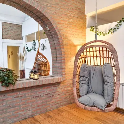 a wicker chair in a room with a brick wall at Posada Mia Nonna in Villa General Belgrano