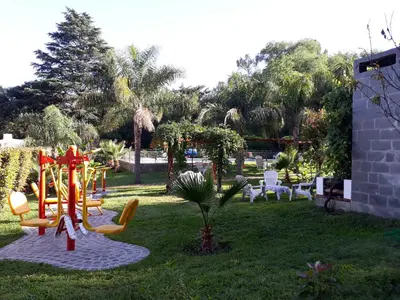 a playground in a yard with chairs and trees at Candy Apart Hotel in Villa General Belgrano