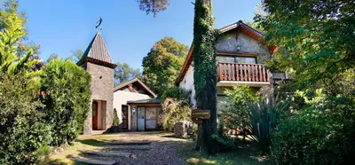 a house with a balcony and a tree at Posada del Sauce in Villa General Belgrano