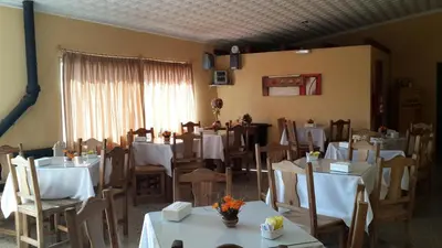 a restaurant with white tables and chairs and a window at Hotel Mirador de las Sierras in Villa Carlos Paz