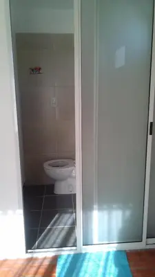 a bathroom with a toilet and a glass door at La Cima Alta Gracia in Alta Gracia