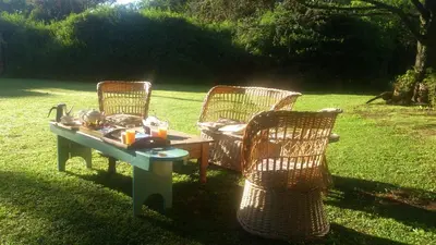 three wicker chairs and a table in the grass at Casita de Piedra B&B in Villa del Dique