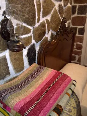 a blanket on a bed next to a stone wall at Casita de Piedra B&B in Villa del Dique