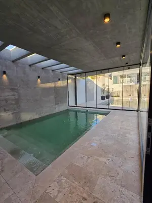 an indoor swimming pool with green water in a building at Hotel Alpre in Villa Carlos Paz