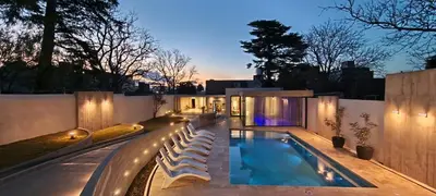 a swimming pool with benches next to a house at Hotel Alpre in Villa Carlos Paz