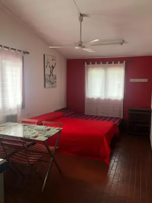 a bedroom with a red bed and a glass table at Departamentos Centricos Carlos Paz in Villa Carlos Paz
