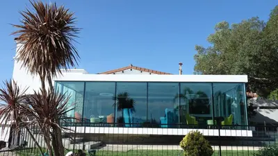 a house with glass windows and a palm tree at Hotel Marqués del Lago in Villa Carlos Paz