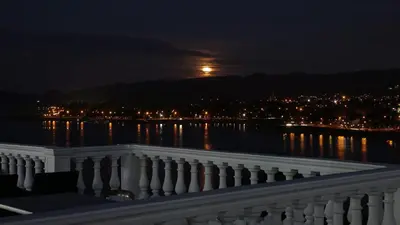 a view of the moon over the water at night at Hotel Marqués del Lago in Villa Carlos Paz