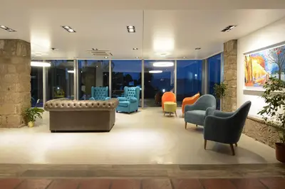 a lobby with chairs and tables and windows at Hotel Marqués del Lago in Villa Carlos Paz