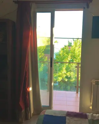 a bedroom with a sliding glass door to a balcony at Paz y Armonia Habitaciones in Mina Clavero