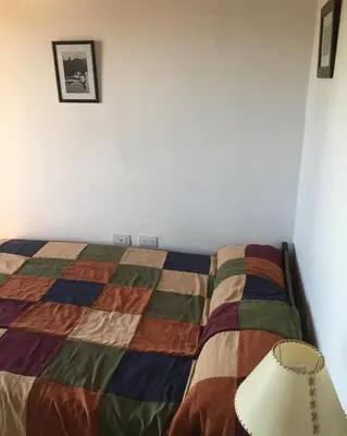 a bedroom with a bed with a colorful quilt at Paz y Armonia Habitaciones in Mina Clavero