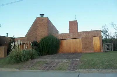 a brick house with a wooden garage at Homero y Martín Coronado in Villa Carlos Paz