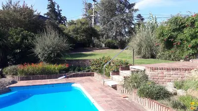 a swimming pool in a garden with a brick wall and stairs at Homero y Martín Coronado in Villa Carlos Paz
