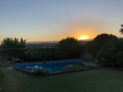 a sunset over a swimming pool in a yard at Homero y Martín Coronado in Villa Carlos Paz