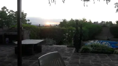 a patio with a table and a sunset in the background at Homero y Martín Coronado in Villa Carlos Paz