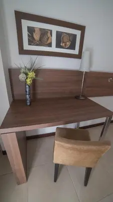 a wooden desk with a vase of flowers and a chair at Hotel Estilo MB - Villa Carlos Paz in Villa Carlos Paz