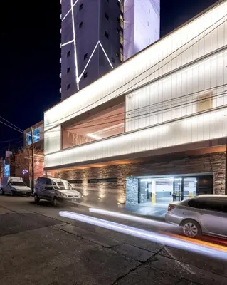 a building with cars parked on a street at night at Hotel Estilo MB - Villa Carlos Paz in Villa Carlos Paz