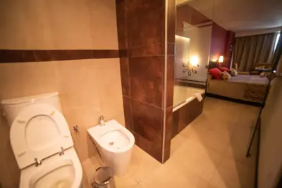 a bathroom with a toilet and a bed in a room at Hotel Estilo MB - Villa Carlos Paz in Villa Carlos Paz