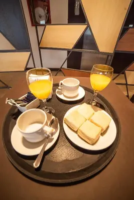 a table with two glasses of orange juice and bread at Hotel Estilo MB - Villa Carlos Paz in Villa Carlos Paz